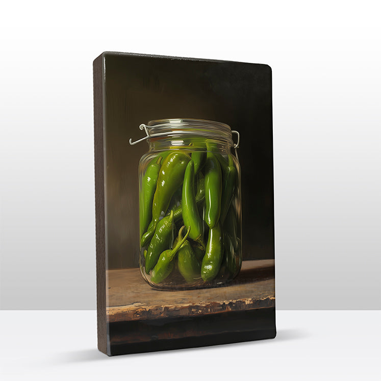 121. Groene pepers in een glazen pot op houten paneel(tje) klein